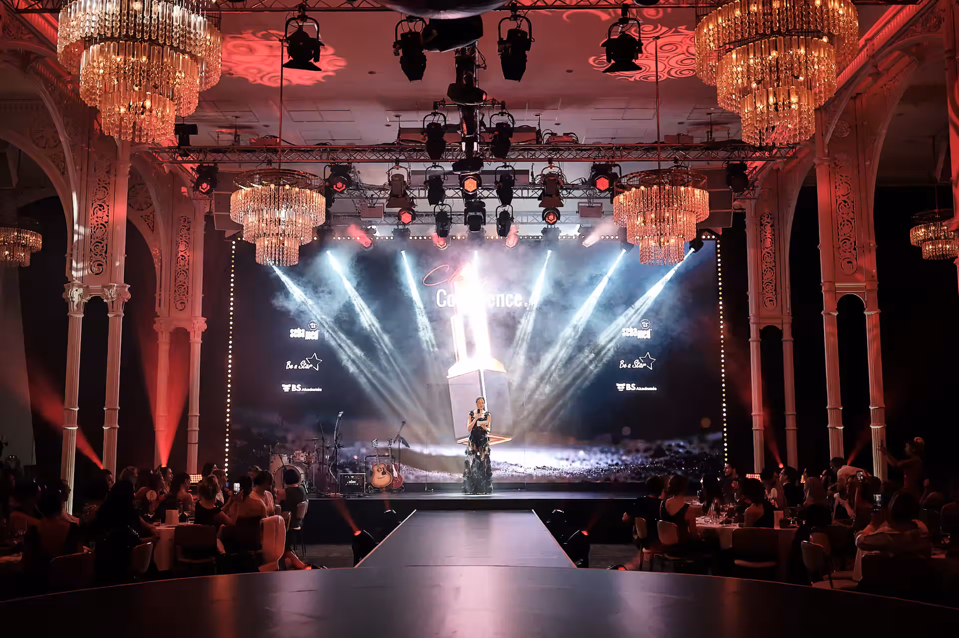 Konzerthalle mit roter Backsteinarchitektur und Publikum bei einem Konzert mit Scheinwerfern und Nebelmaschine